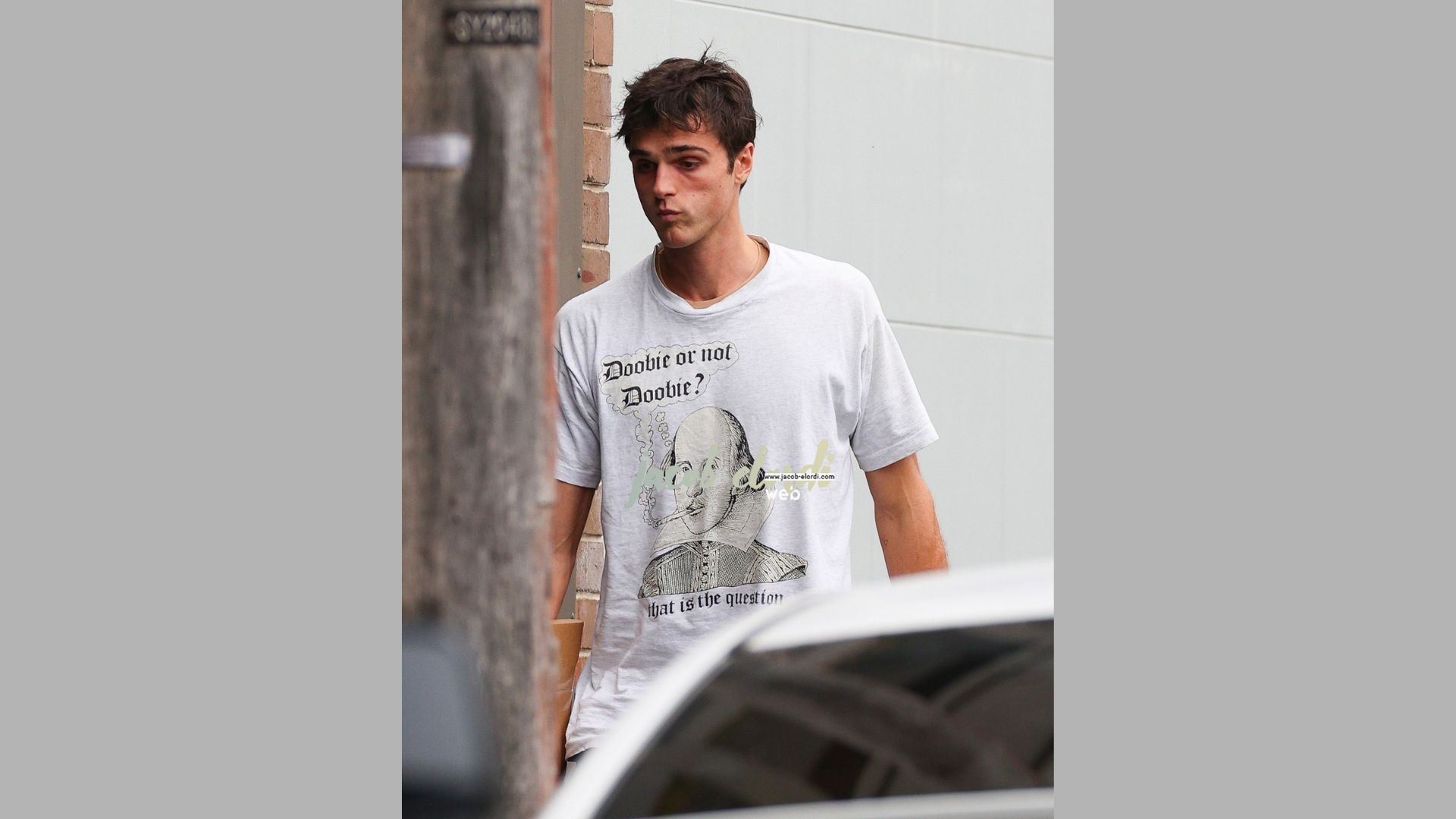 A man in a t-shirt featuring an image of another man, standing casually with a neutral background.