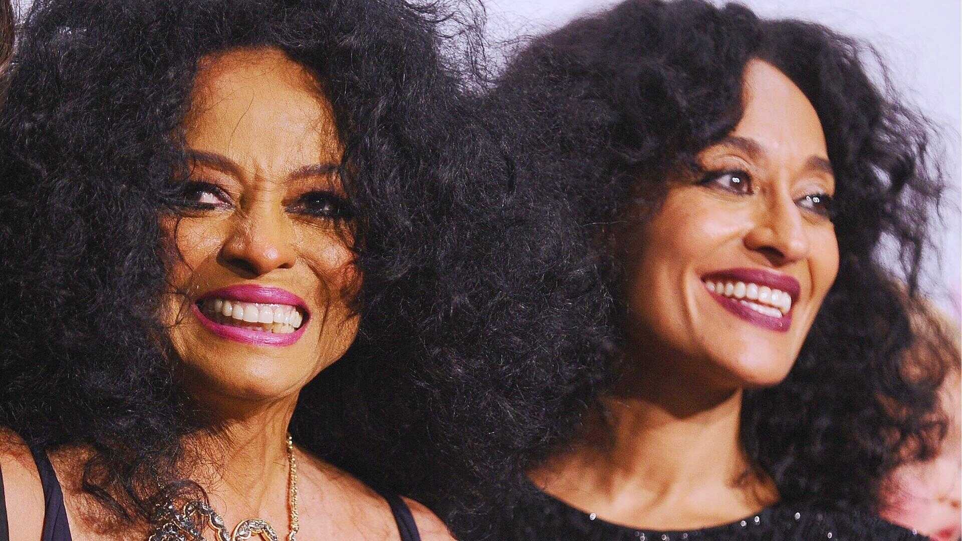 Diana Ross and Tracee Ellis Ross pose smiling with matching voluminous natural curls and magenta lipstick at red carpet event.