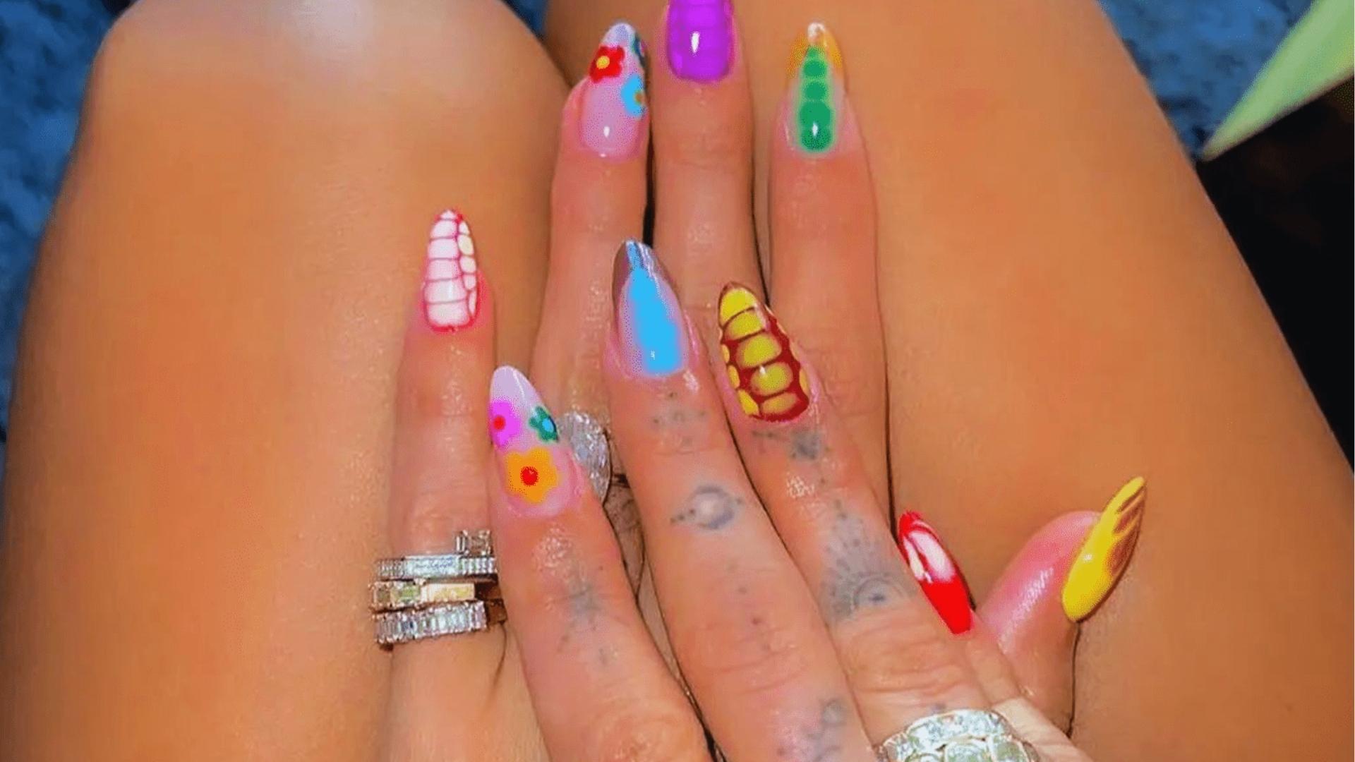 Close-up of long almond nails with colorful mix-and-match art, bright florals, crocodile print, chrome, and neon shades in Hailey’s playful style.