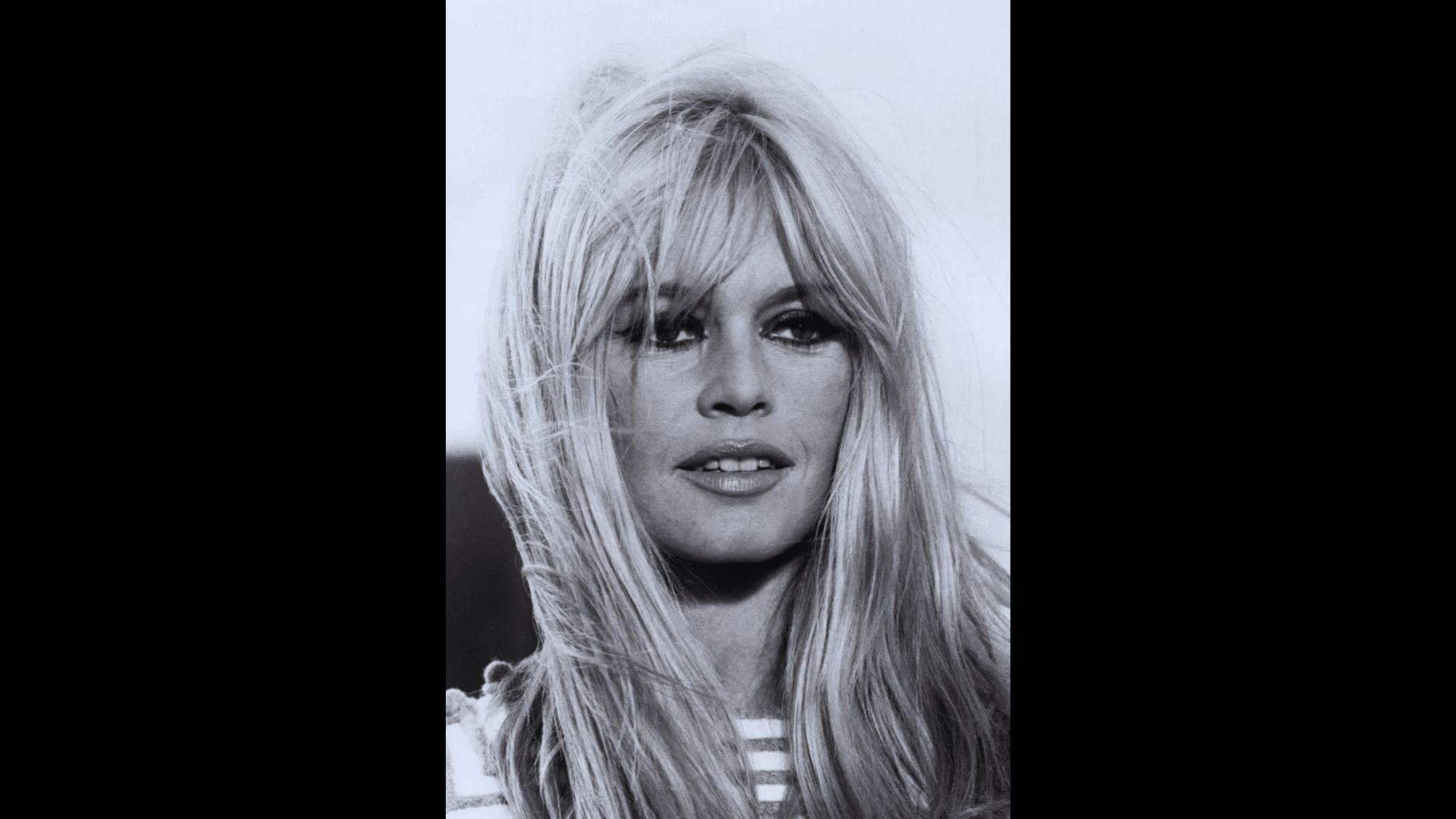 Black and white portrait of Brigitte Bardot with long curtain bangs framing her face.