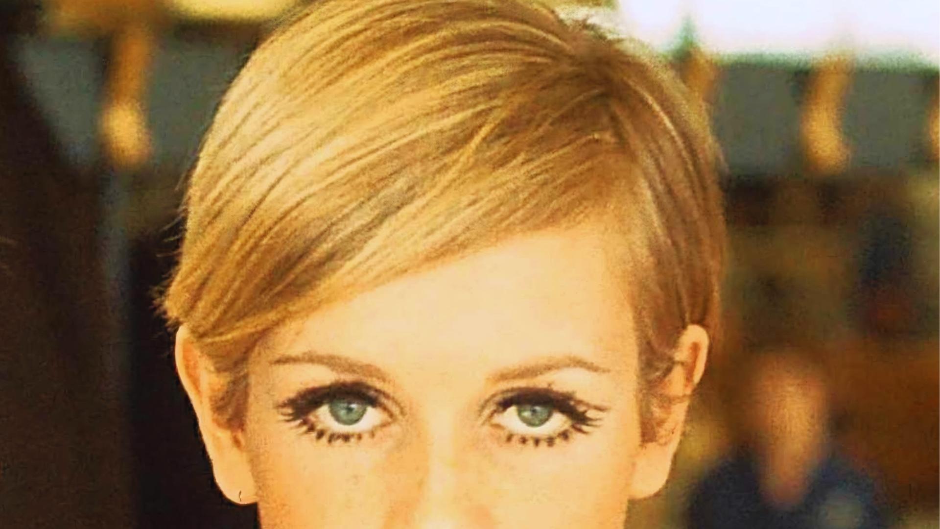 Vintage shot of Twiggy with iconic blonde crop, deep side part, and graphic painted lashes defining the original 60s look.