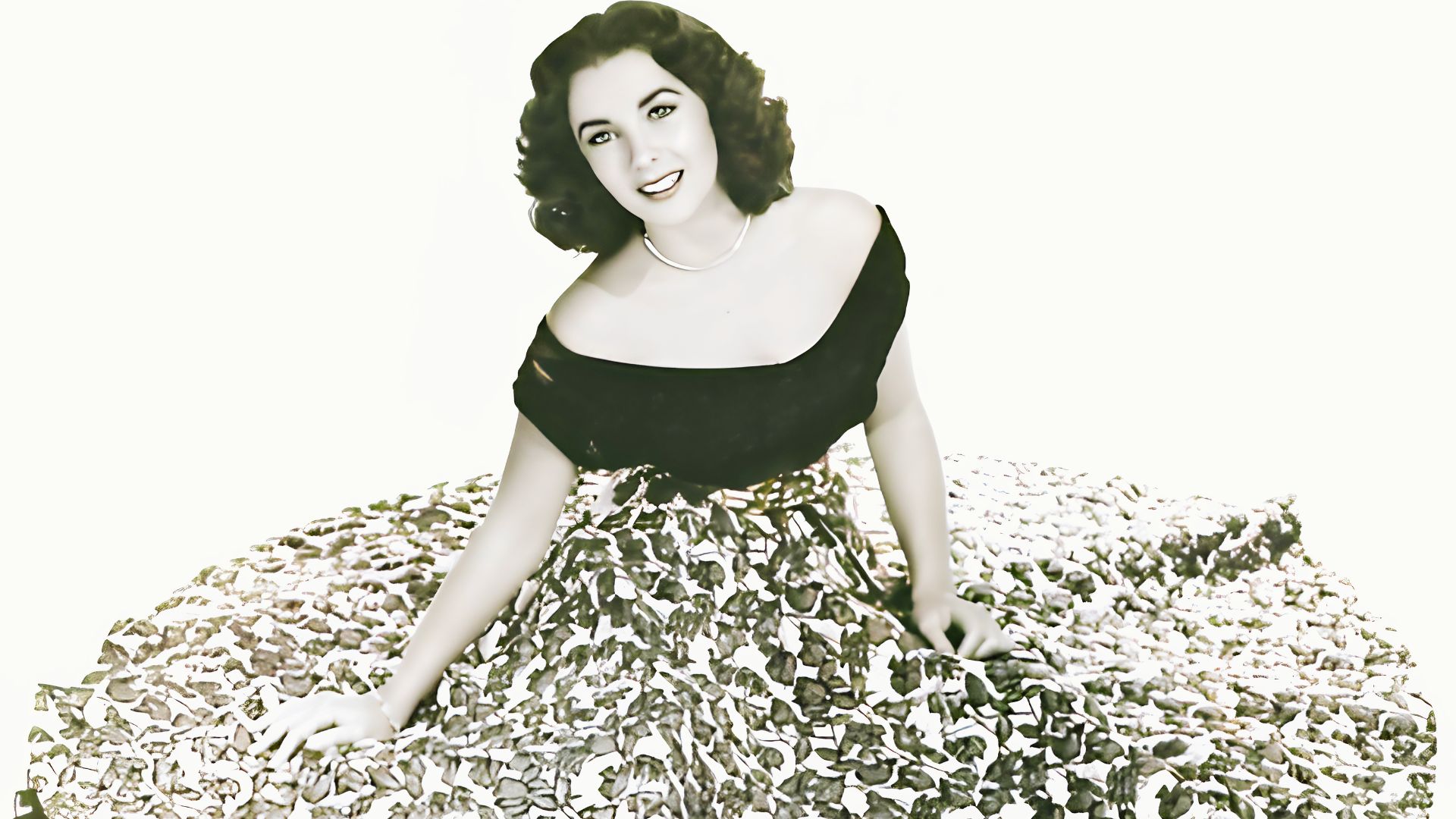 Elizabeth Taylor in a black off-shoulder top with a full floral print skirt.