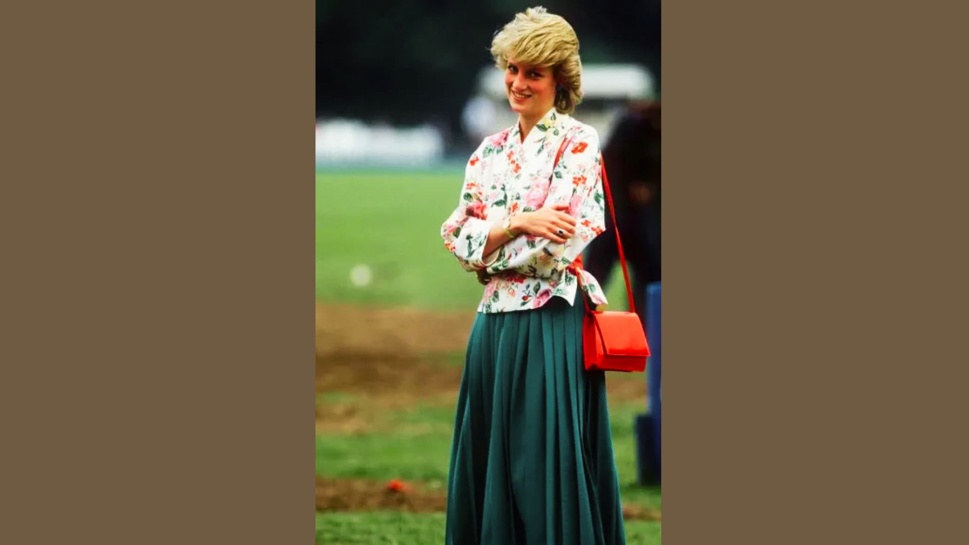 Princess Diana stands on a field in a white floral kimono-style blouse and emerald pleated skirt.