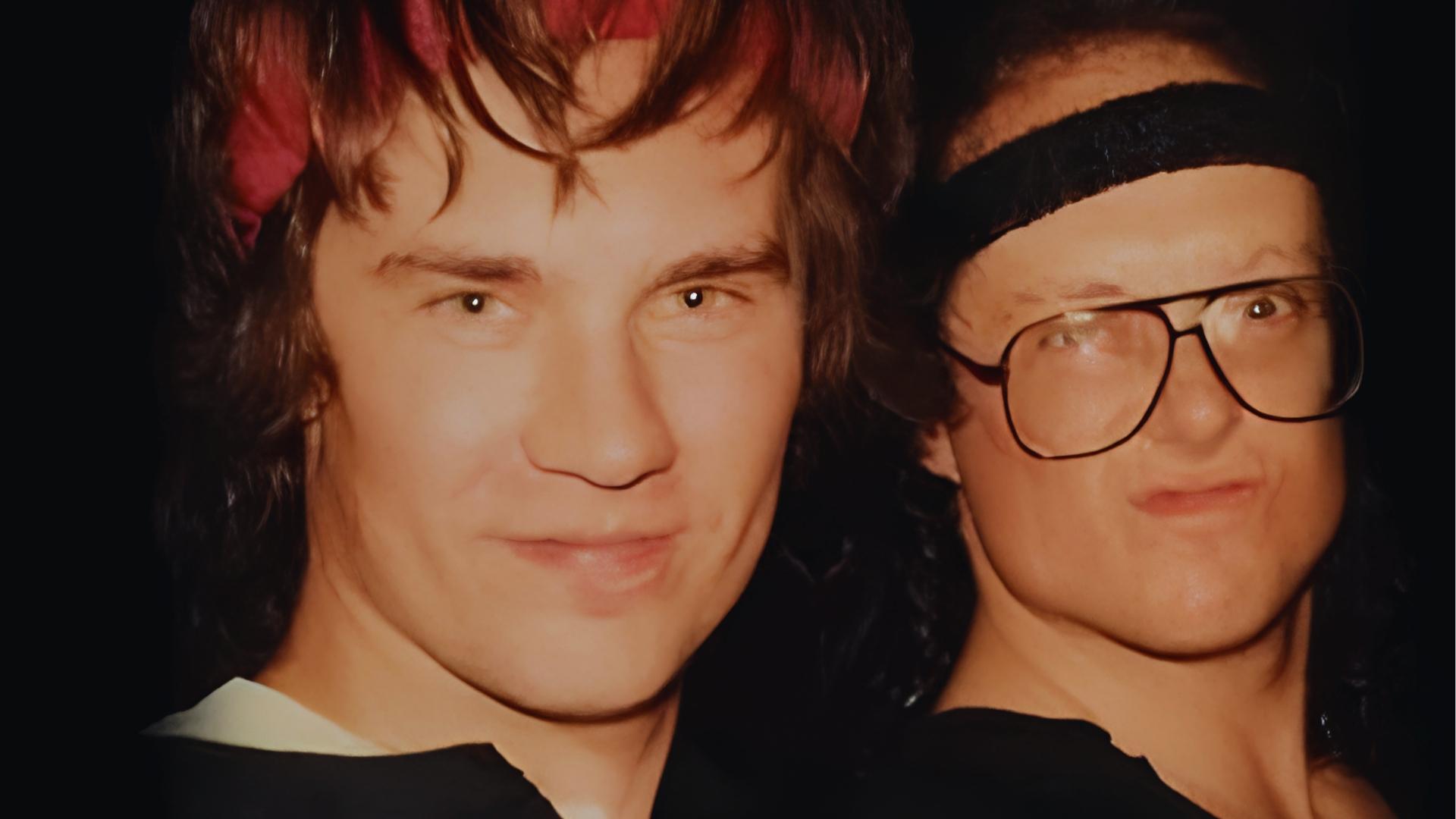 Vintage photo of young Doyle Wolfgang von Frankenstein with wet brown hair and red bandana poses beside a man with glasses.