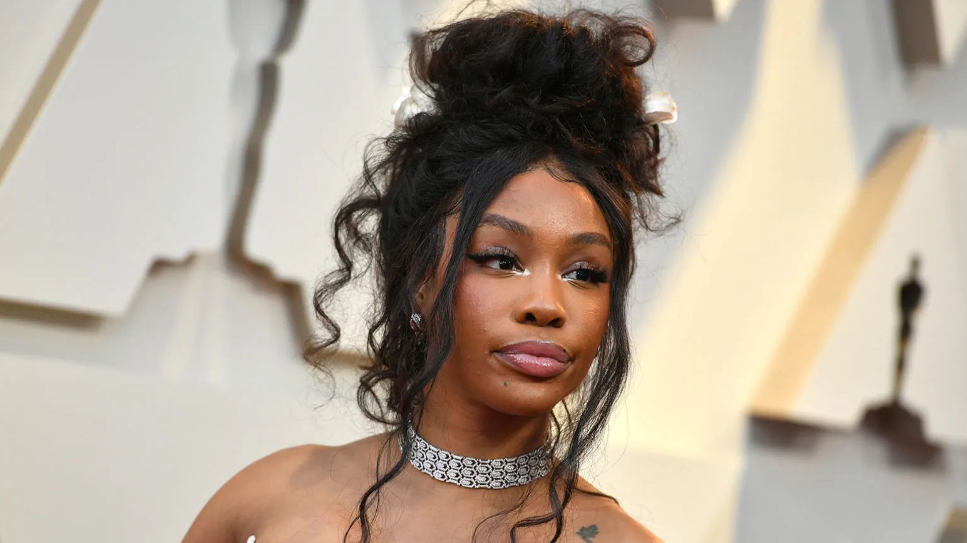 SZA with a messy bun hairstyle wearing a necklace, showcasing a casual and stylish look.