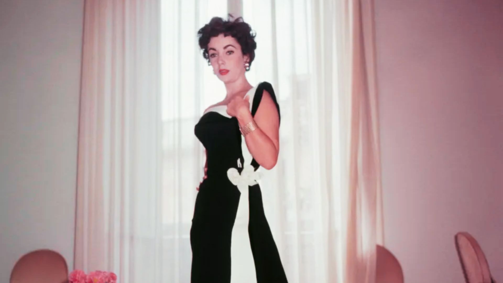 Elizabeth Taylor poses in a form-fitting black velvet gown with a white panel and large bow detail.