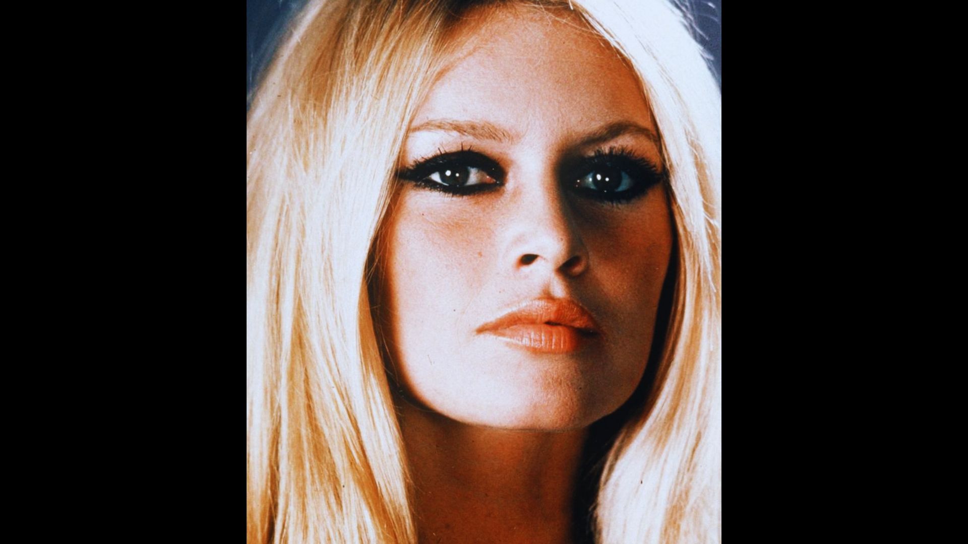 Brigitte Bardot close-up with dramatic 1960s smoky eye makeup and blonde hair under evening lighting.