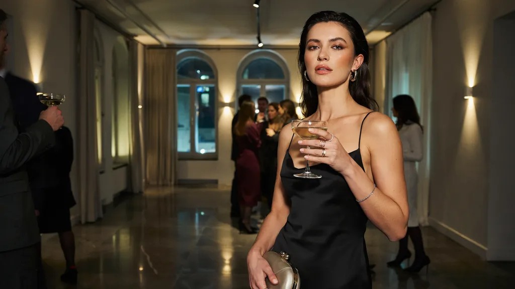 Woman wearing a black semi formal outfit with metallic accessories.