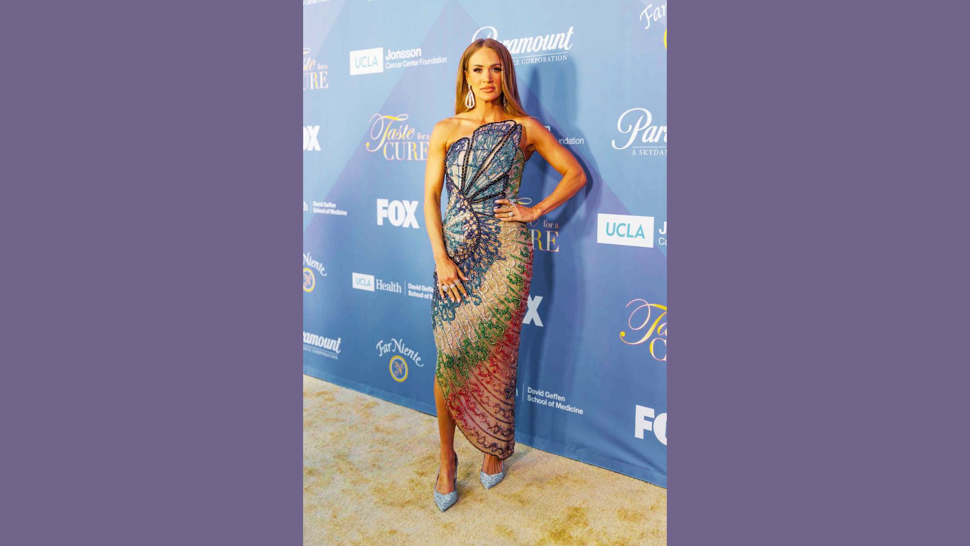 Carrie Underwood posing confidently in a bold red carpet gown at a celebrity event