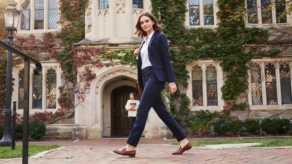 Woman wearing classic preppy clothing with polished accessories outdoors.