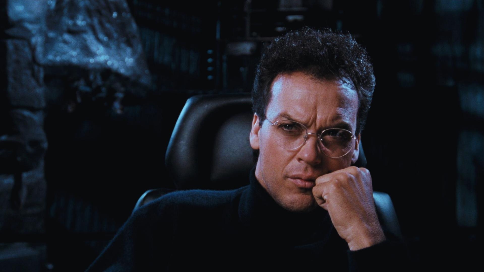 Michael Keaton as Bruce Wayne with curly hair and round glasses in Batcave in Batman 1989.