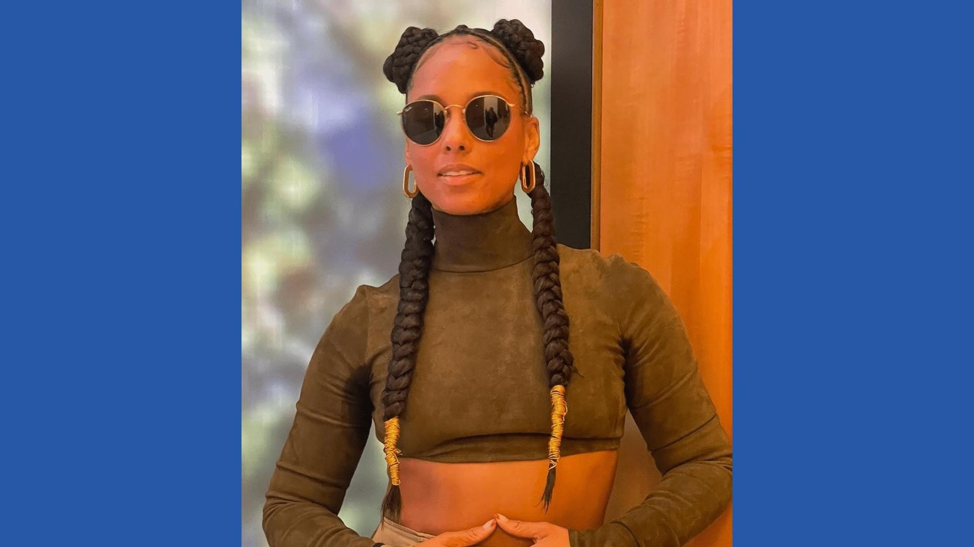 Alicia Keys rocks two chunky braided buns with long braids down back, gold-wrapped ends, round sunglasses, olive crop turtleneck.
