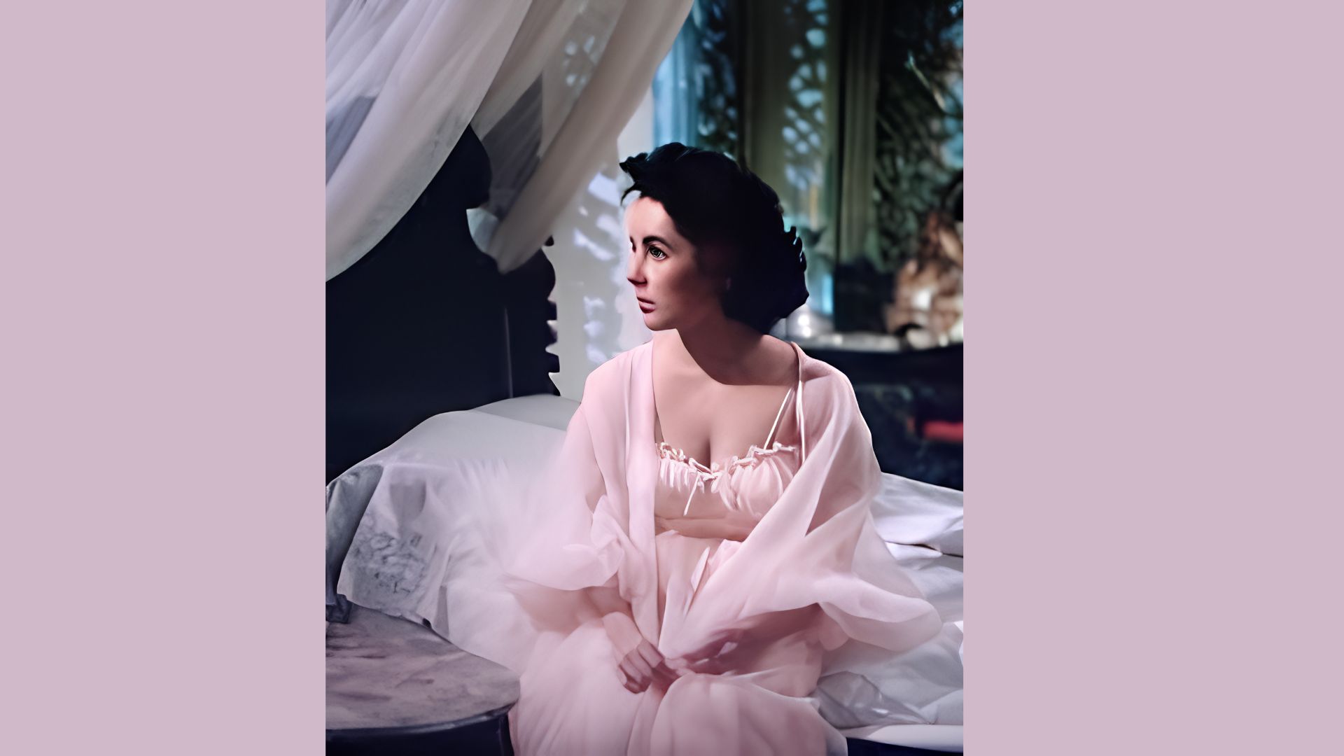 Elizabeth Taylor reclines on a sofa in a white embroidered halter gown with statement diamond earrings.
