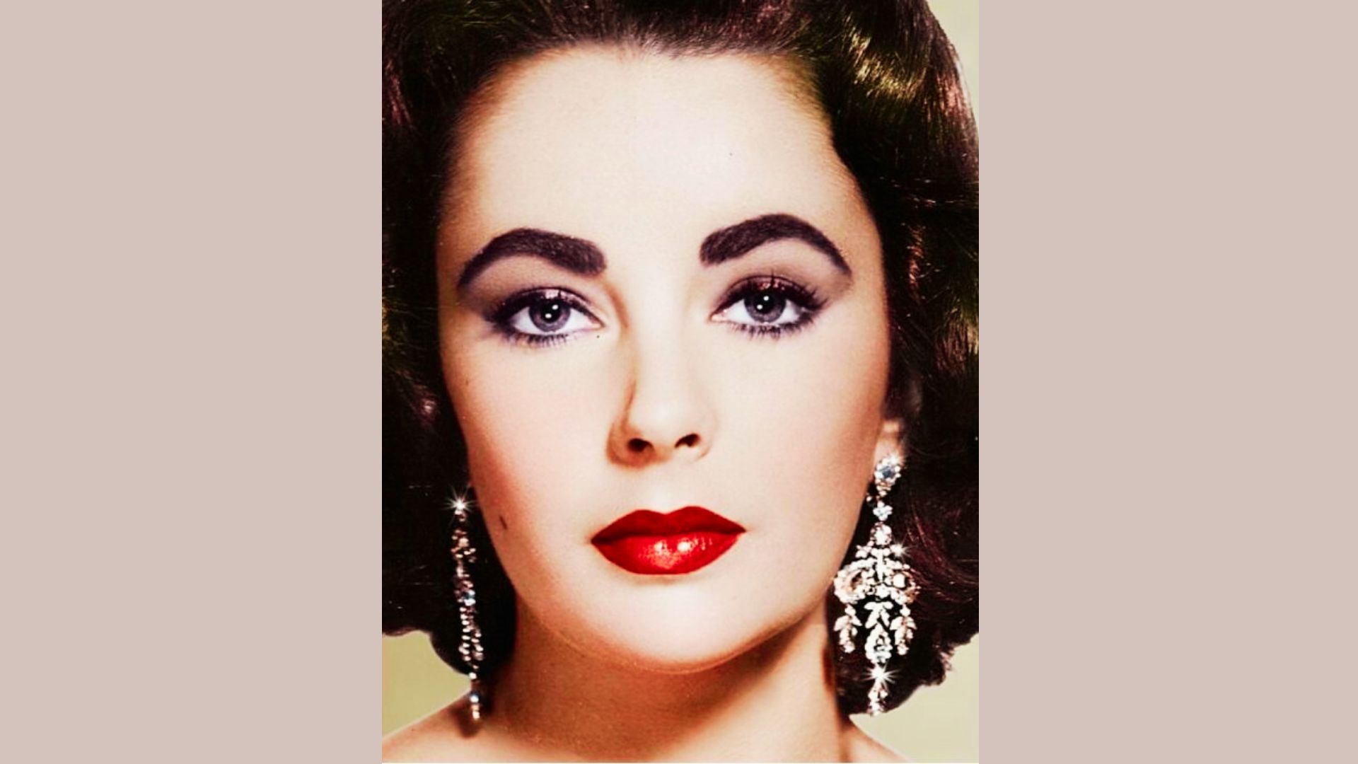 Close-up of Elizabeth Taylor with flawless red lips, violet eyes, and sculpted brows in 1950s glamour style.