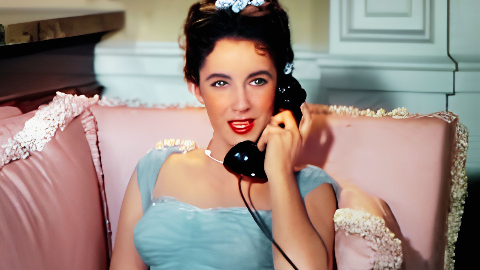 Young Elizabeth Taylor on a vintage telephone, dressed in a pale blue 1950s gown with pearl accents.