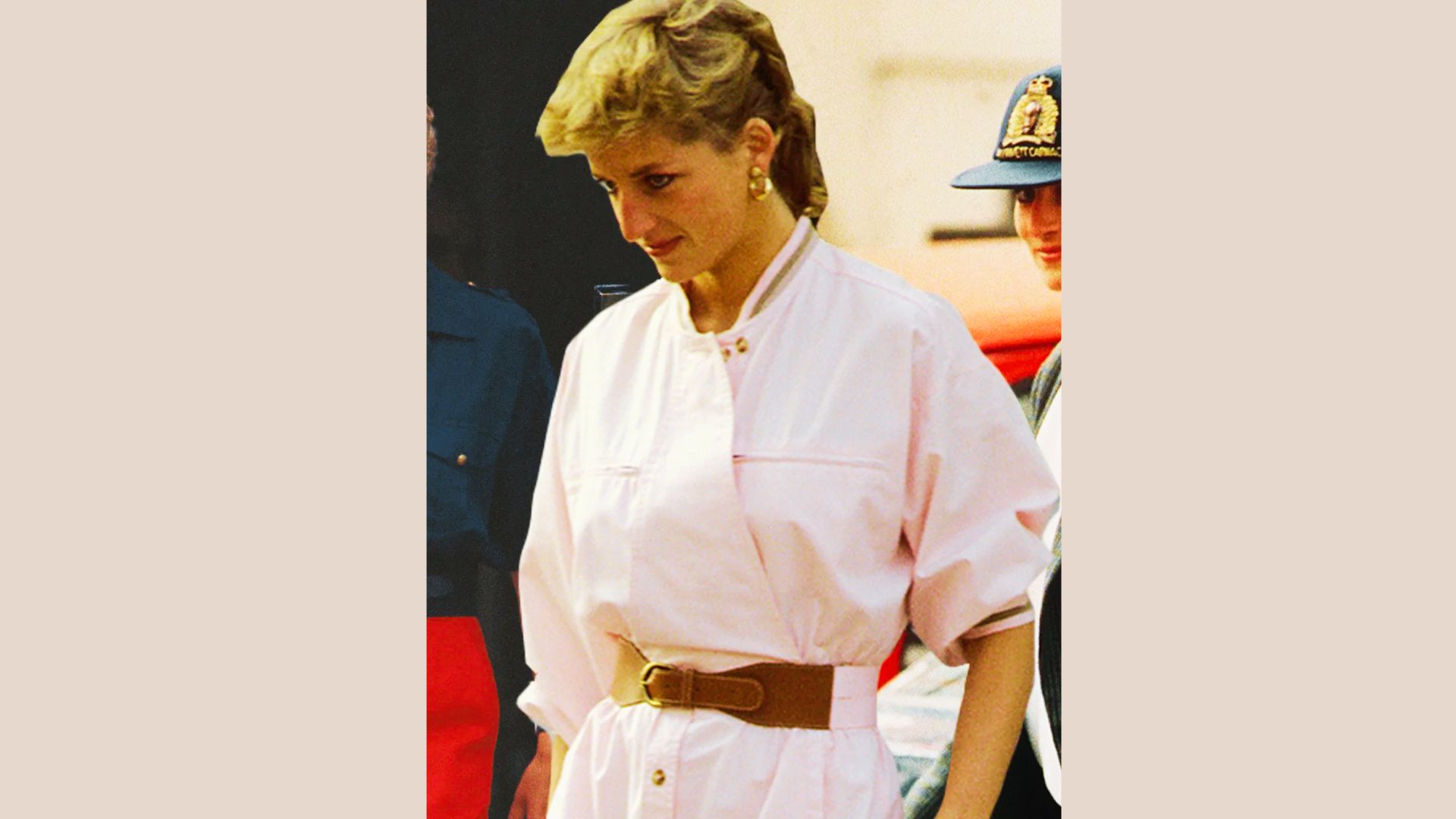 Princess Diana wears a pastel pink belted shirtdress with rolled sleeves and a wide brown belt.