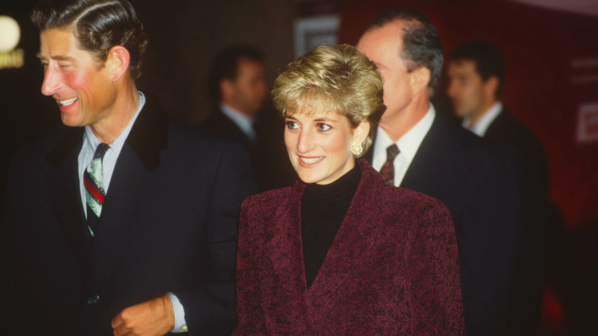 Princess Diana attends an event in a textured burgundy wool coat layered over a black turtleneck sweater.