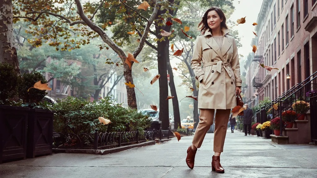 Trench coat layered over knitwear for a fall preppy outfit.