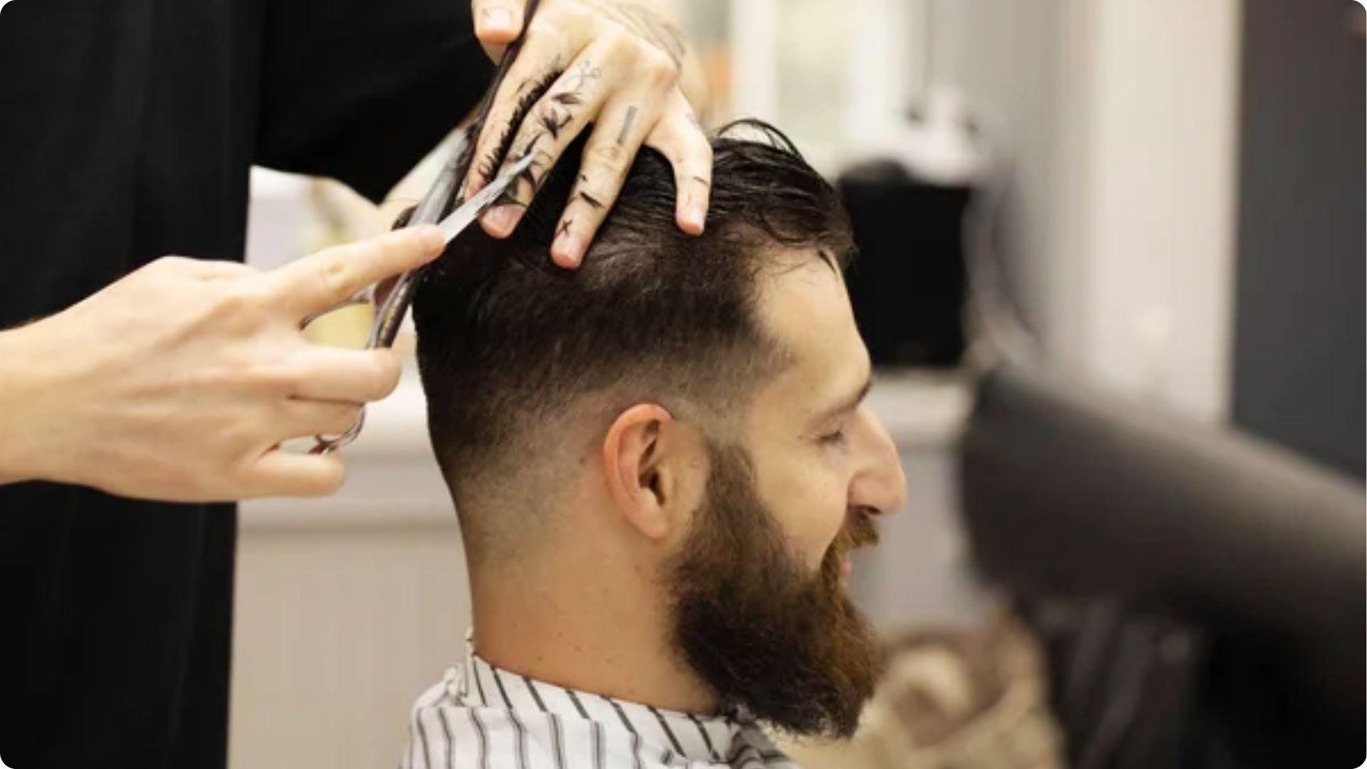 Barber cutting textured short fade haircut on bearded man, Ryan Reynolds style inspiration look