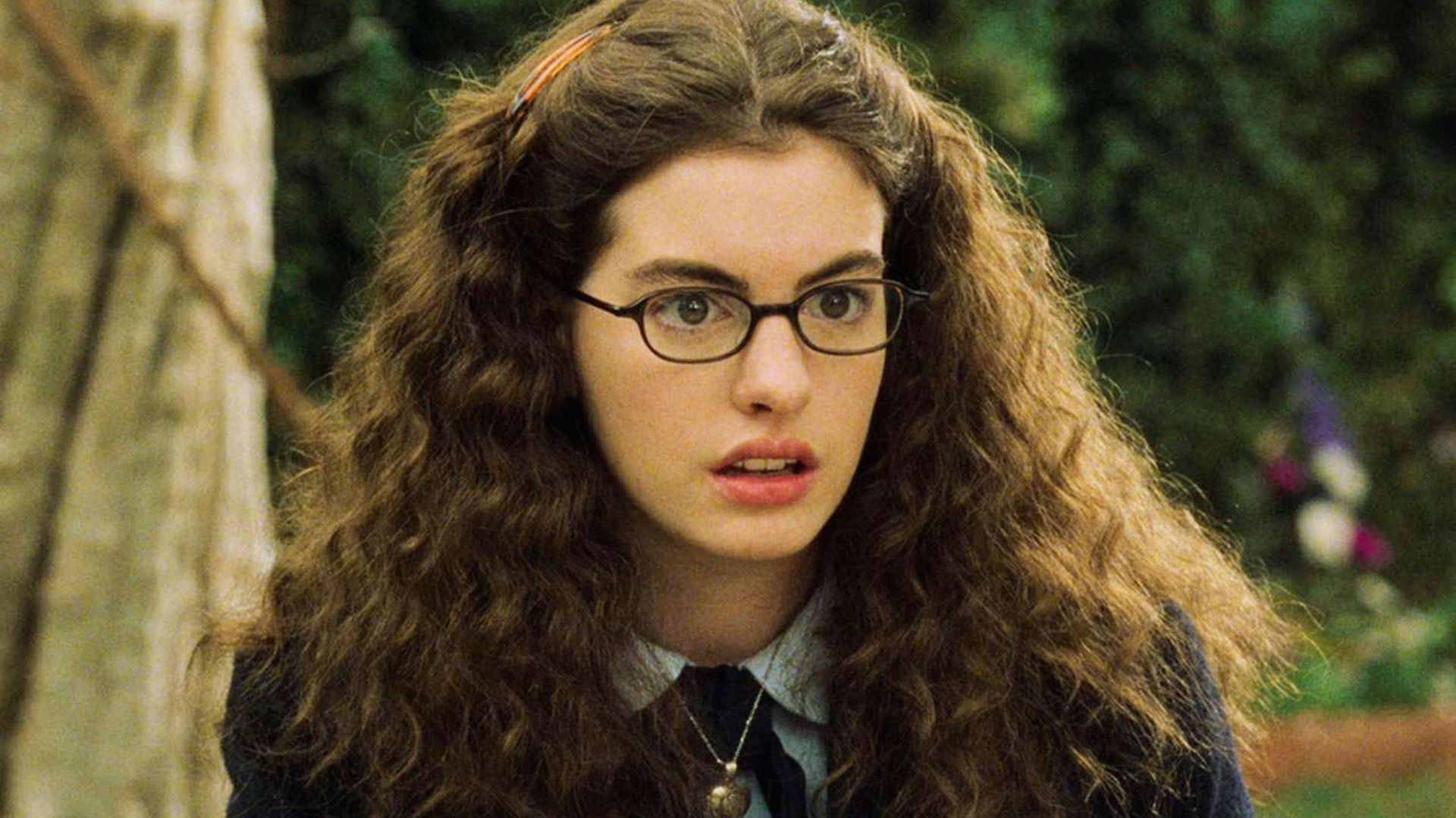 Young Anne Hathaway Princess Diaries curly hair, glasses, and school uniform.