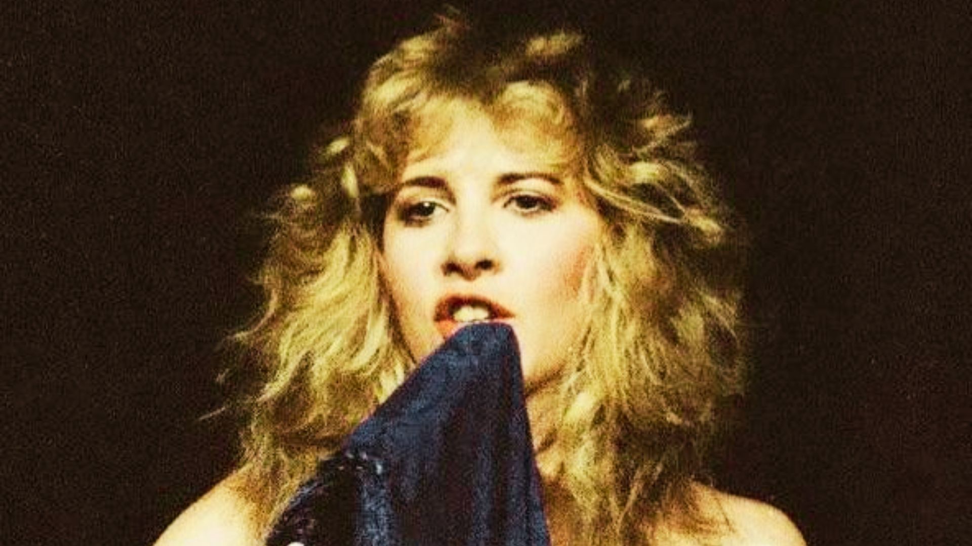 Vintage-style photo of Stevie Nicks in profile with dark, tightly curled ringlets cascading past her shoulders.