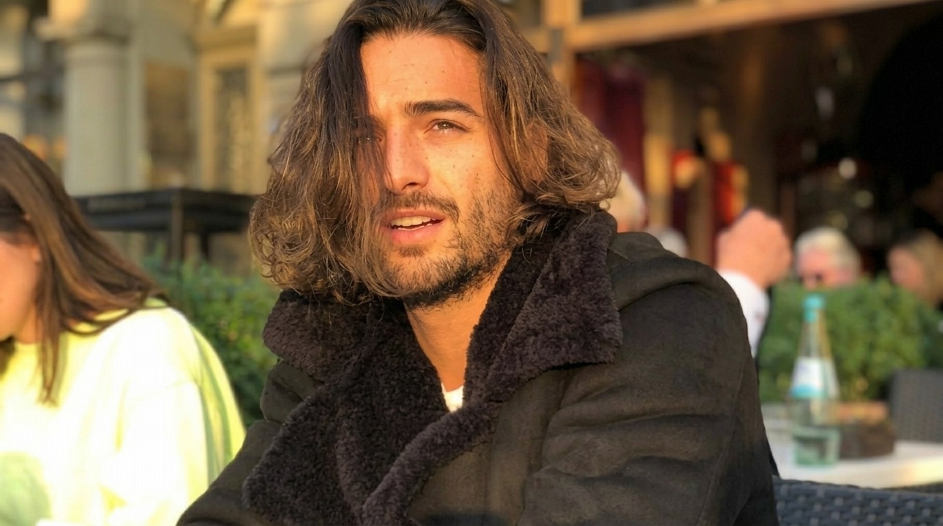 Maluma with natural shoulder-length wavy long hair parted in middle at cafe