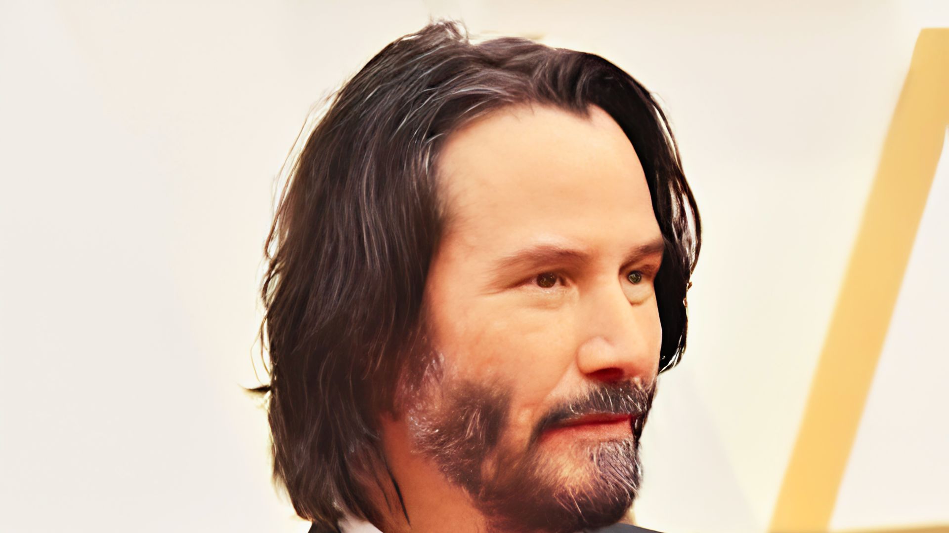 Keanu Reeves sports long, straight hair past his shoulders with a salt-and-pepper beard.