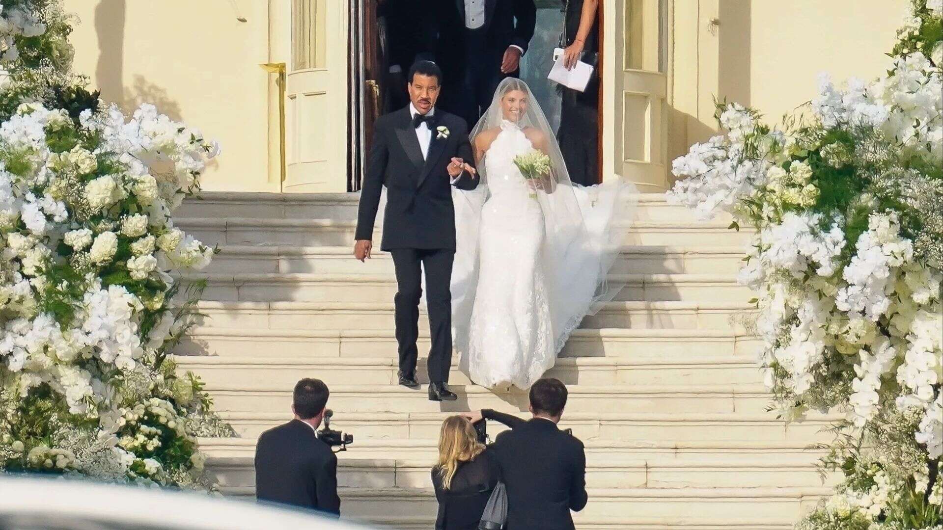 Sofia Richie in her Chanel wedding dress walking down the steps with father Lionel Richie beside her.