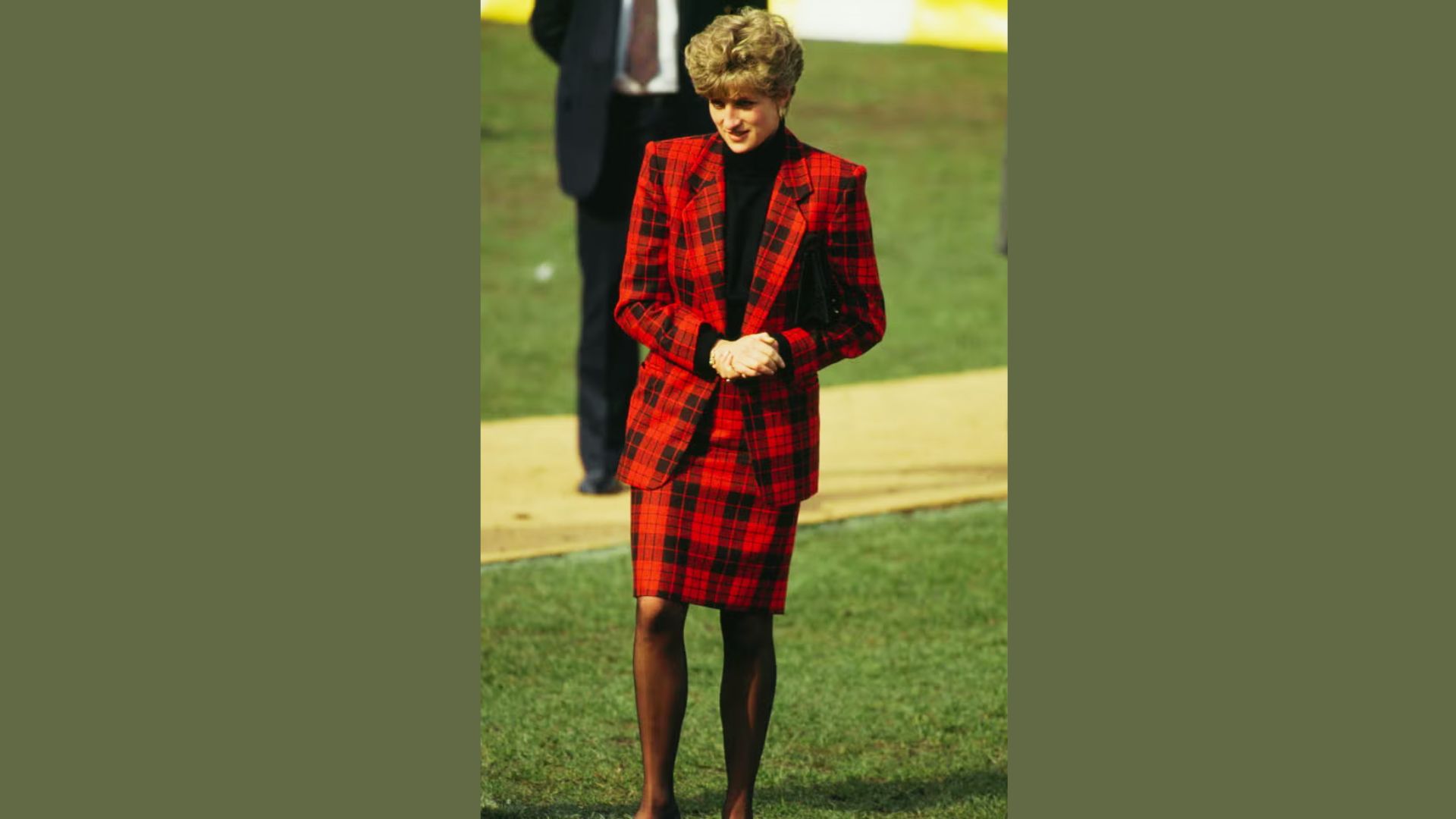 Princess Diana stands on grass in a bold red tartan blazer and matching pencil skirt.