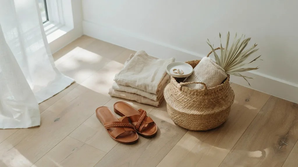 Tan leather sandals styled with linen clothing in a bright coastal home.
