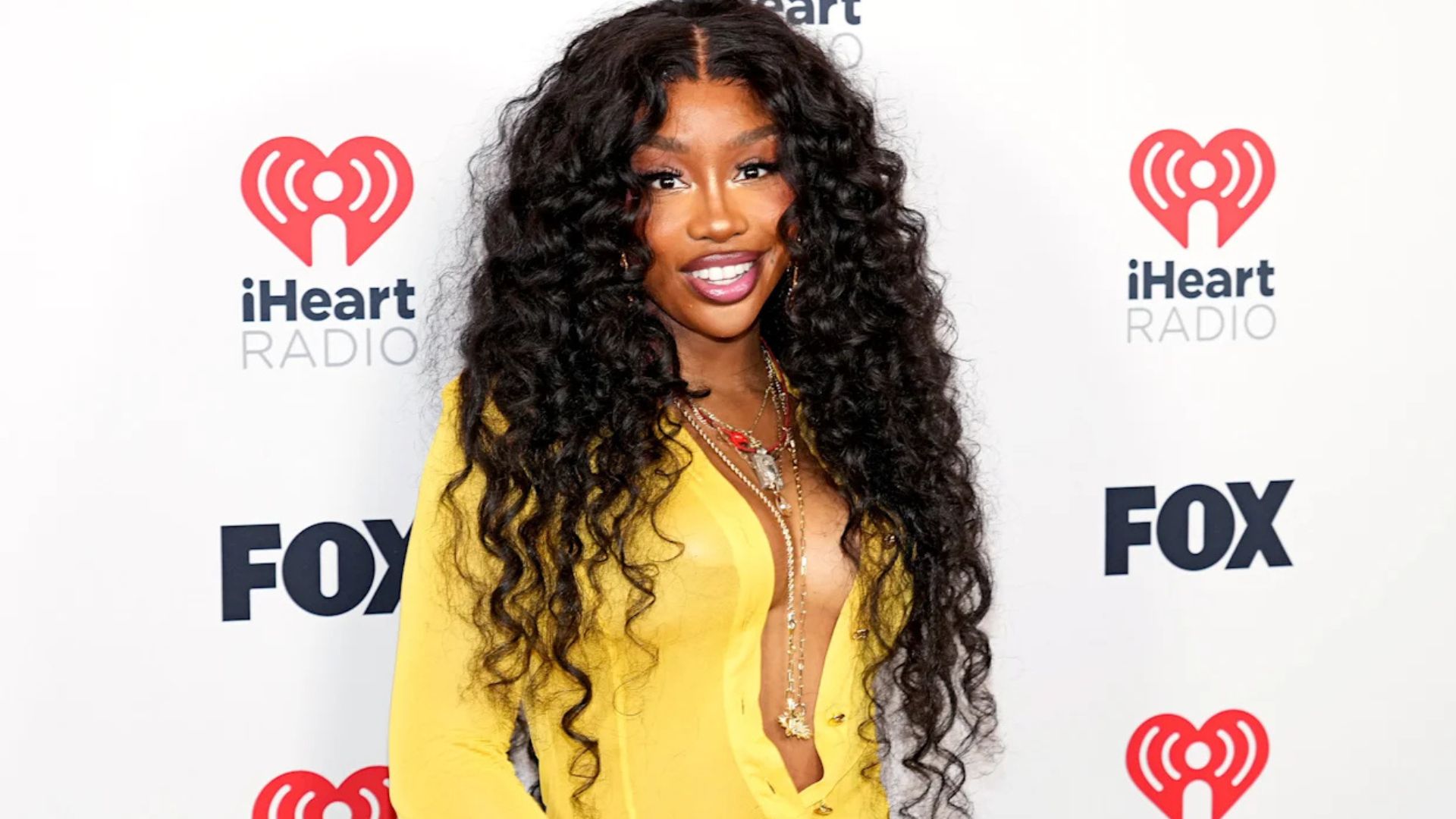 A close-up of SZA showcasing a high puff hairstyle, emphasizing her natural curls and radiant expression.