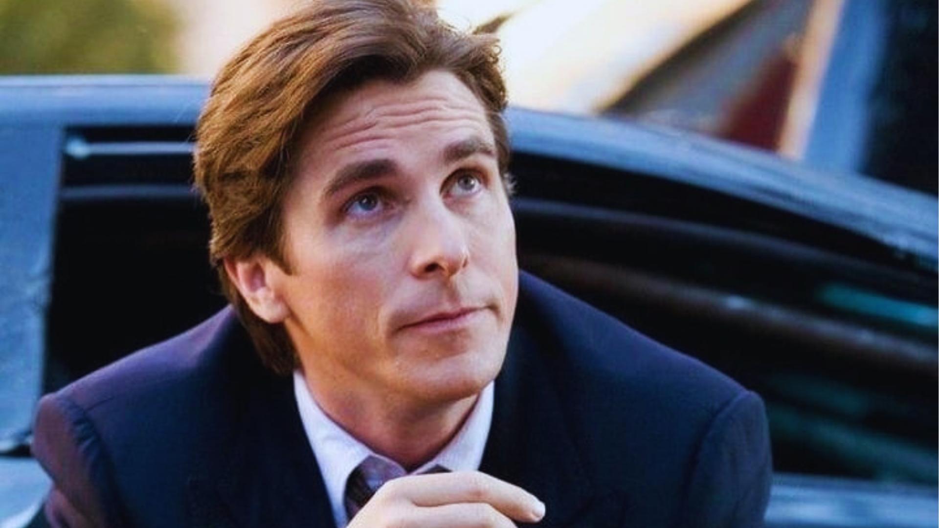 Christian Bale as Bruce Wayne with longer feathered hair stepping out of a car in The Dark Knight.