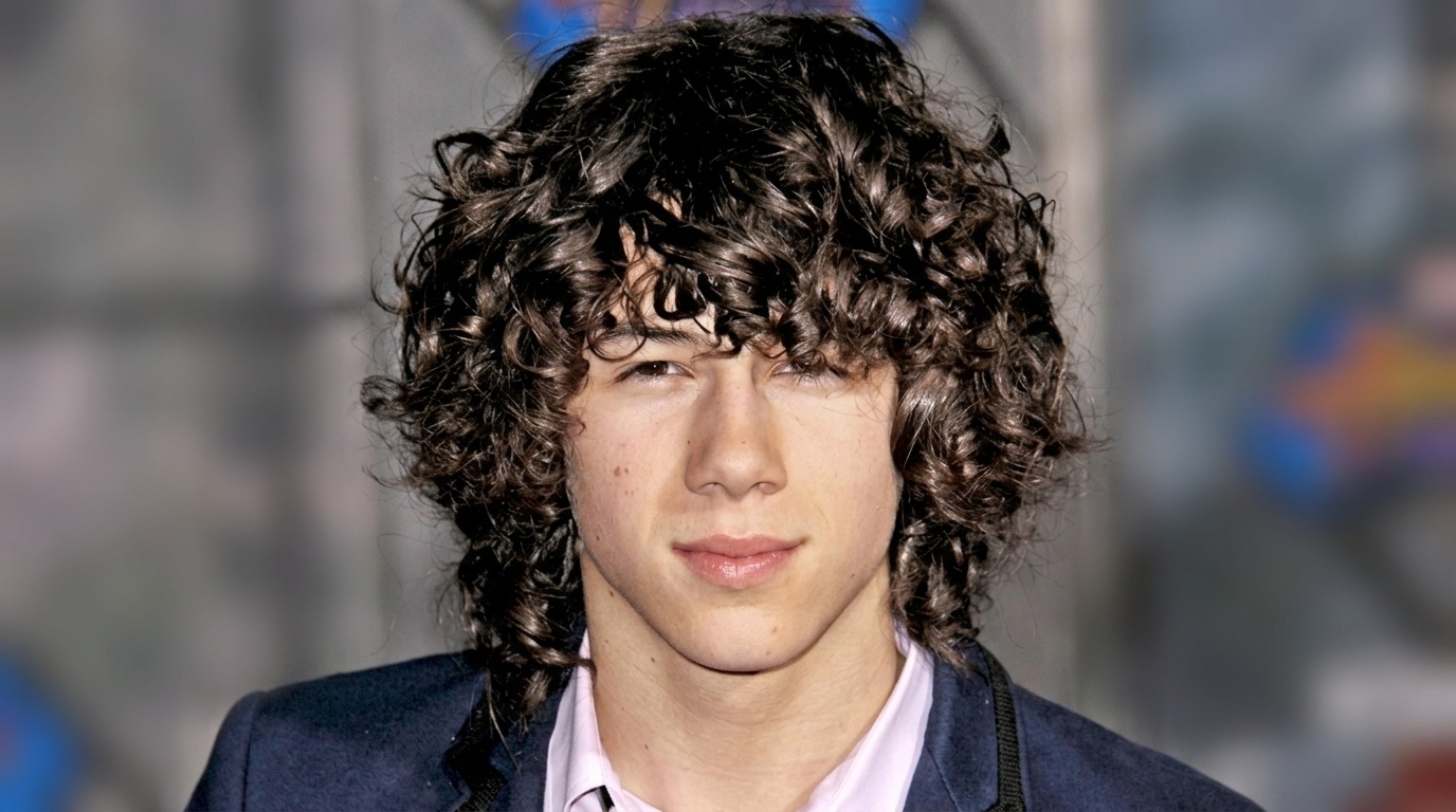 Young Nick Jonas with long voluminous curly hair as a teenager