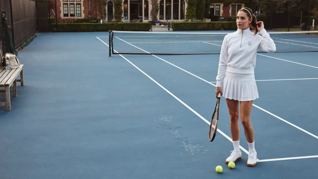 Tennis skirt styled with a quarter-zip pullover and sneakers.