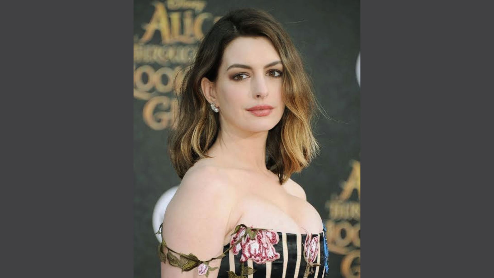 Anne Hathaway posing with a wavy lob haircut with sun-kissed ends and side part