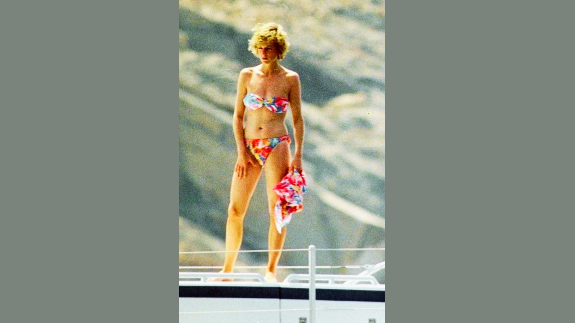 Princess Diana stands on a yacht wearing a colorful floral bandeau bikini.