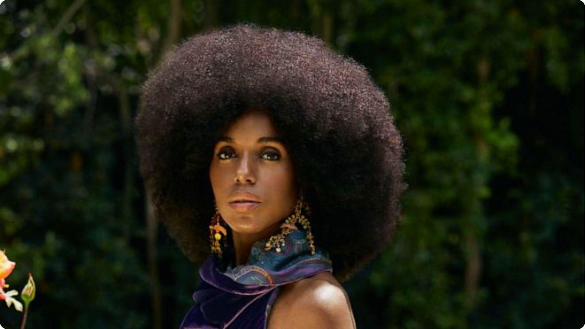 Kerry Washington poses outdoors with large rounded natural afro and purple printed scarf earrings
