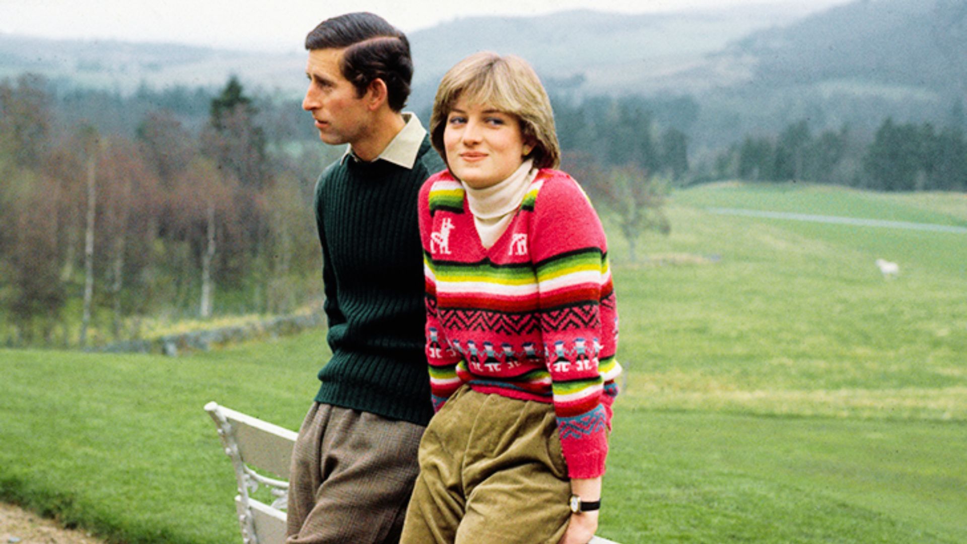Princess Diana stands outdoors with then-Prince Charles in a colorful striped V-neck sweater over a cream turtleneck.