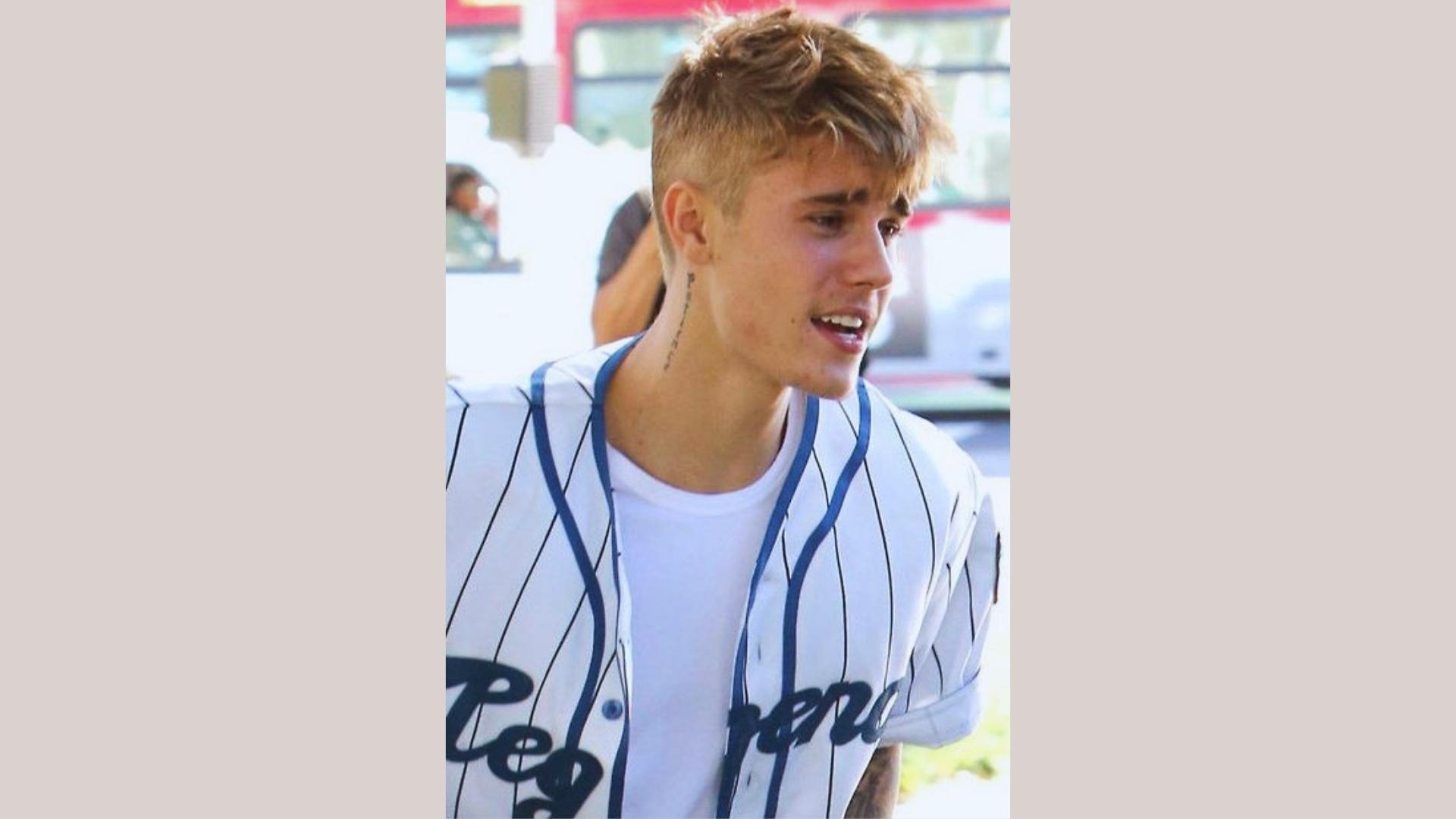 Justin Bieber with textured undercut blonde hair in baseball jersey, iconic short hairstyle.