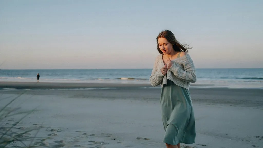 Layered coastal outfit with knit sweater during a beach sunset.