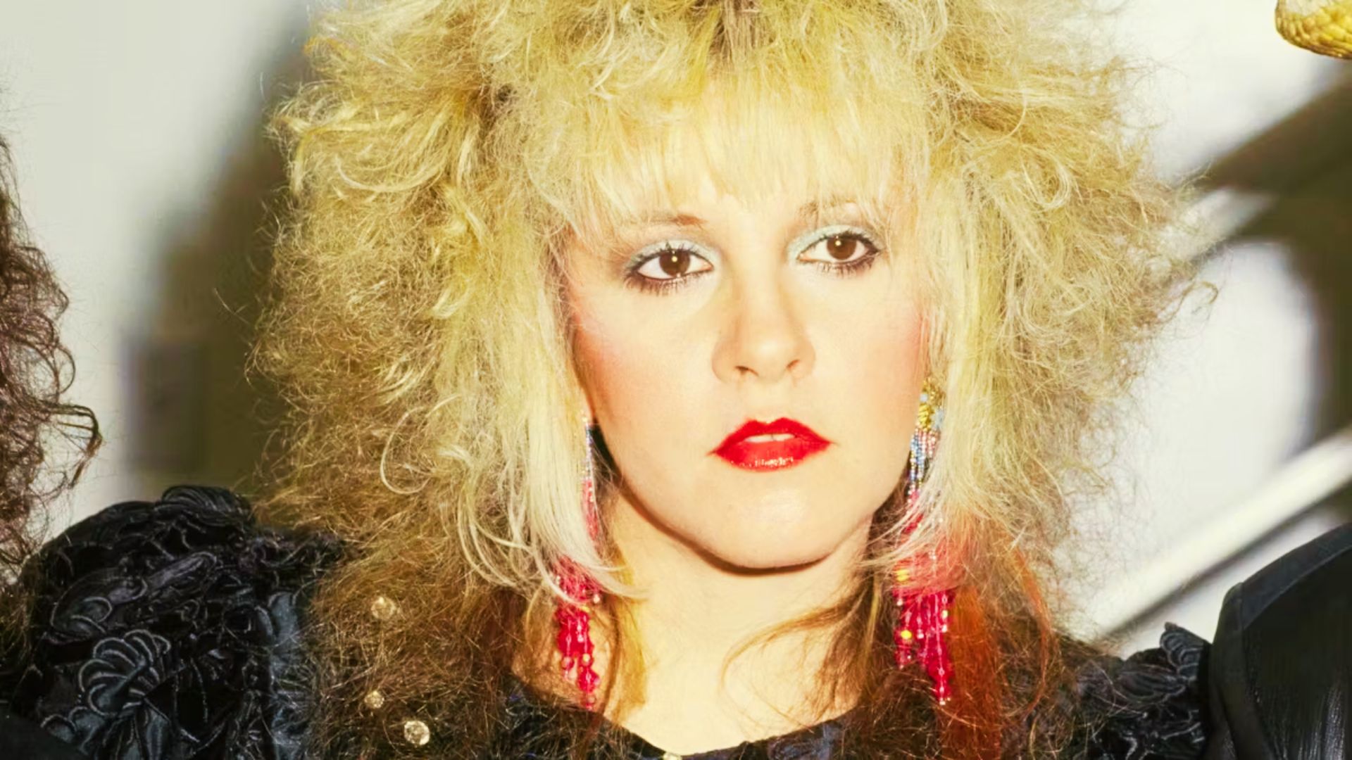 Portrait of Stevie Nicks with soft, golden-blonde waves and full, wispy bangs.