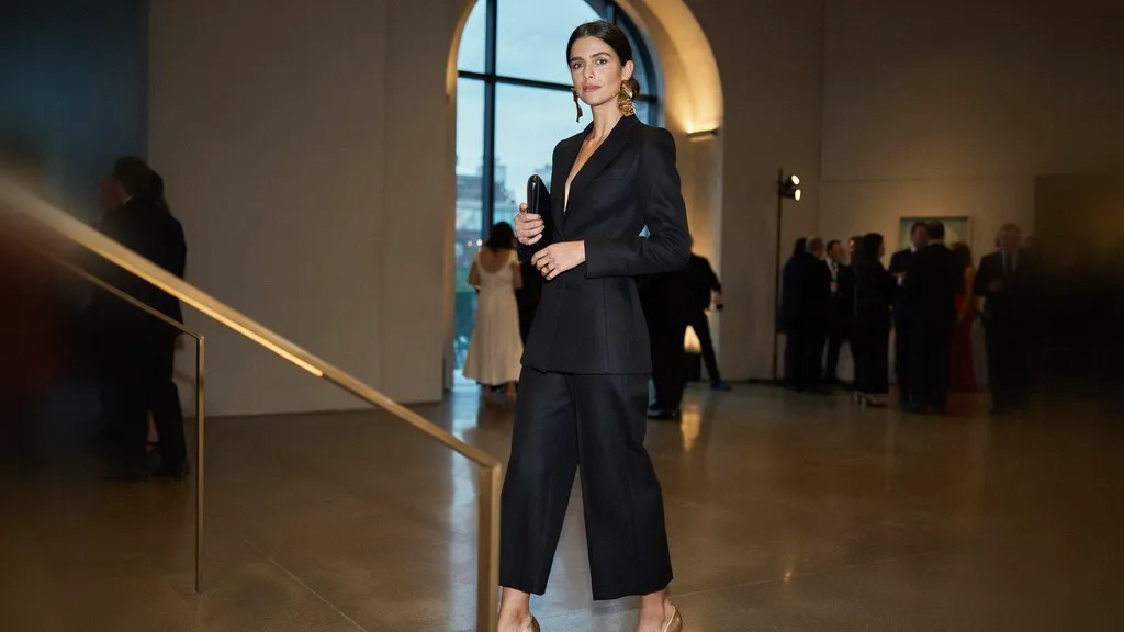 Woman wearing a tailored jumpsuit and statement earrings.
