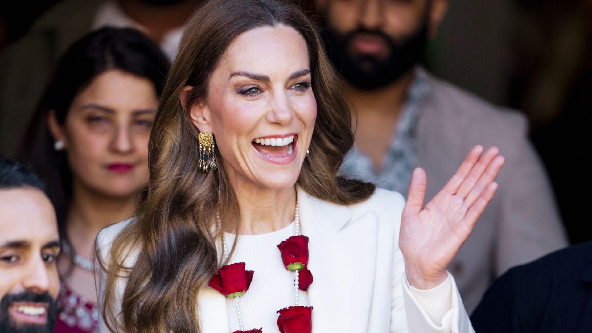 Kate Middleton waves wearing ornate gold earrings and white blazer with red roses at royal engagement