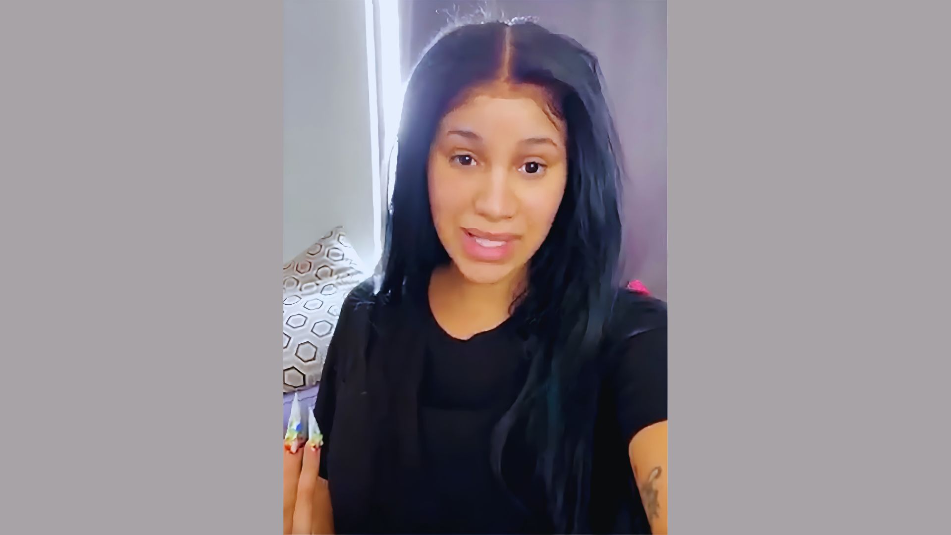 Cardi B appearing makeup-free while applying skincare in a casual social media video.